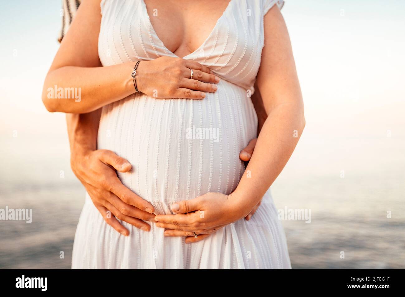 Pregnant woman with her partner holding her belly in the nature Stock Photo