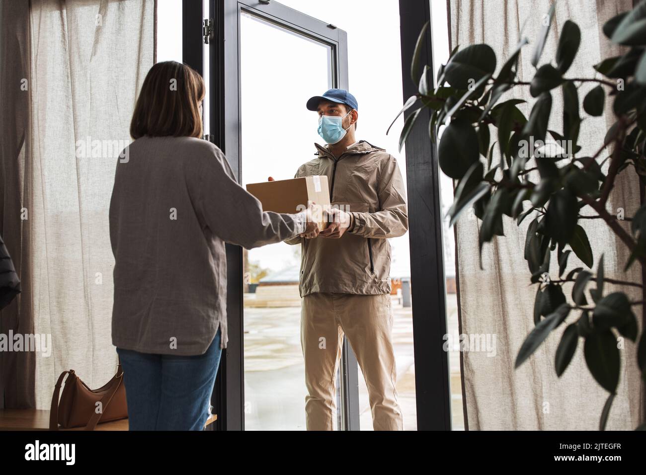 delivery man in mask giving parcel to customer Stock Photo - Alamy