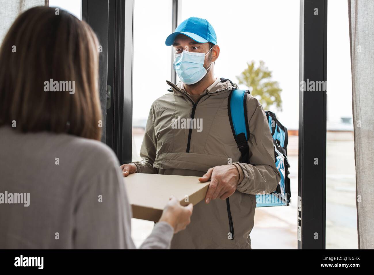 food delivery man in mask giving order to customer Stock Photo - Alamy
