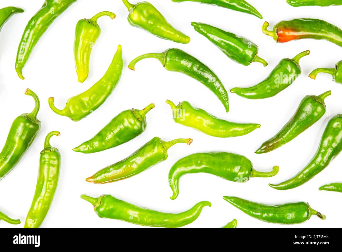 green hot peppers evenly spread on a white background. vitamin