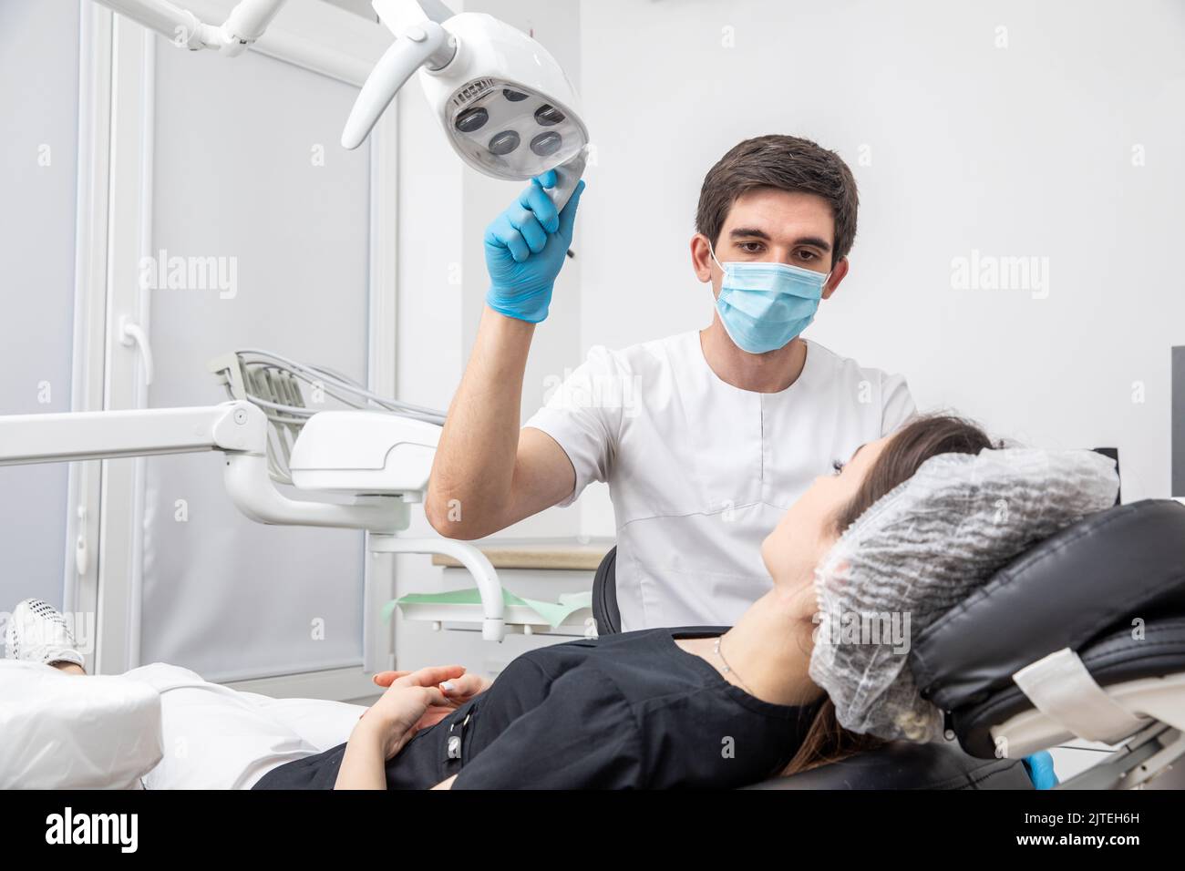 Dentist adjusting dental lamp in dental office. Dentist turning on lamp before treatment Stock Photo