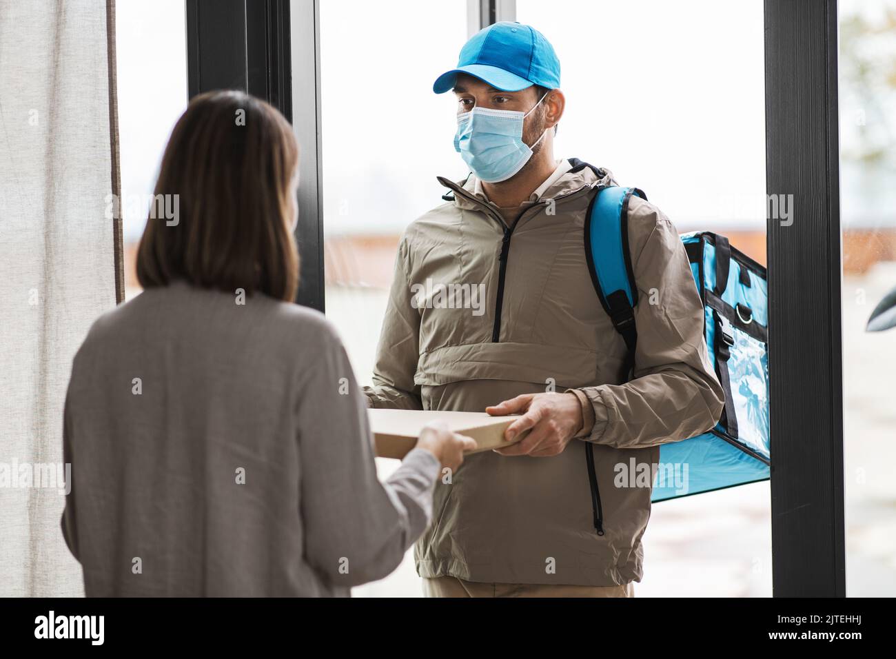 food delivery man in mask giving order to customer Stock Photo - Alamy