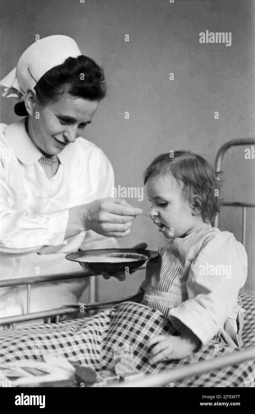 Kampf der Tuberkulose im TBC Kinderkrankenhaus in Neukölln, hier füttert eine Krankenschwester ein Mädchen, Berlin, Deutschland 1947. Stock Photo