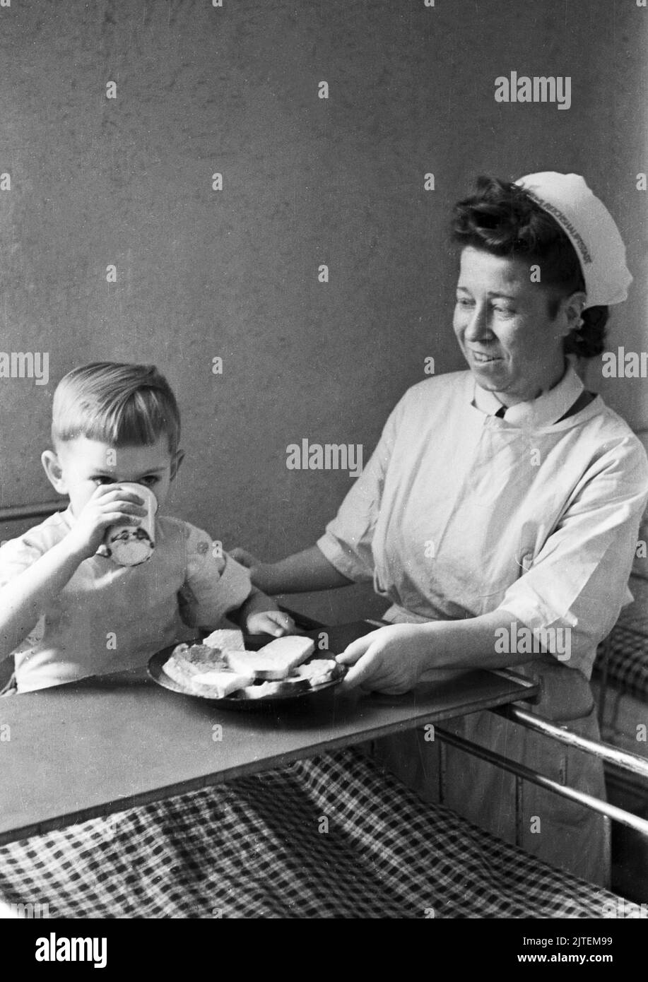 Kampf der Tuberkulose im TBC Kinderkrankenhaus in Neukölln, hier eine Krankenschwester beim Frühstück mit einem kleinen Jungen, Berlin, Deutschland 1947. Stock Photo