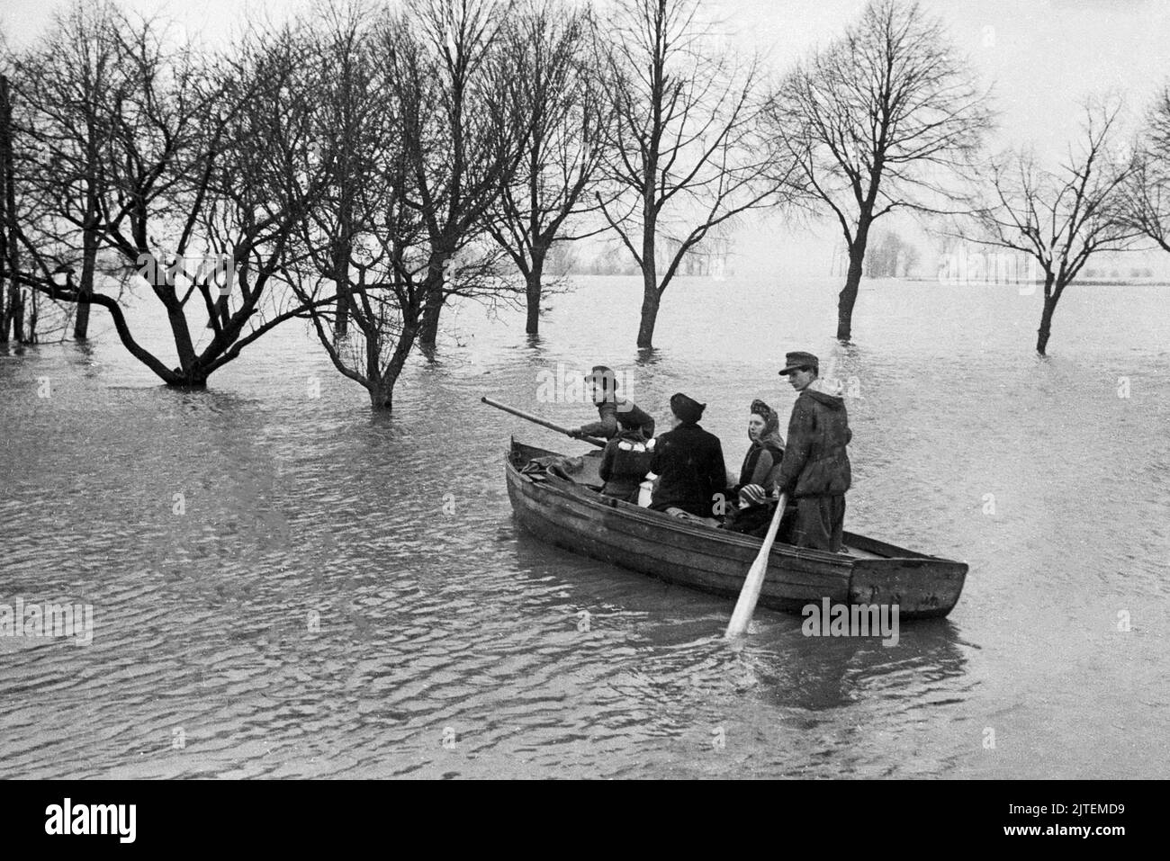 In Paddelbooten werden Anwohner aus ihren Häusern evakuiert während der Hochwasserkatastrophe im Dorf Neutrebbin, Deutschland 1947. Stock Photo