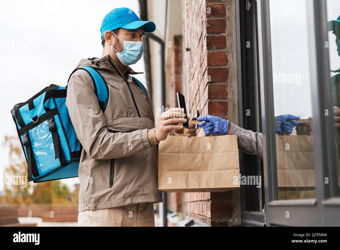 food delivery man in mask giving order to customer Stock Photo - Alamy