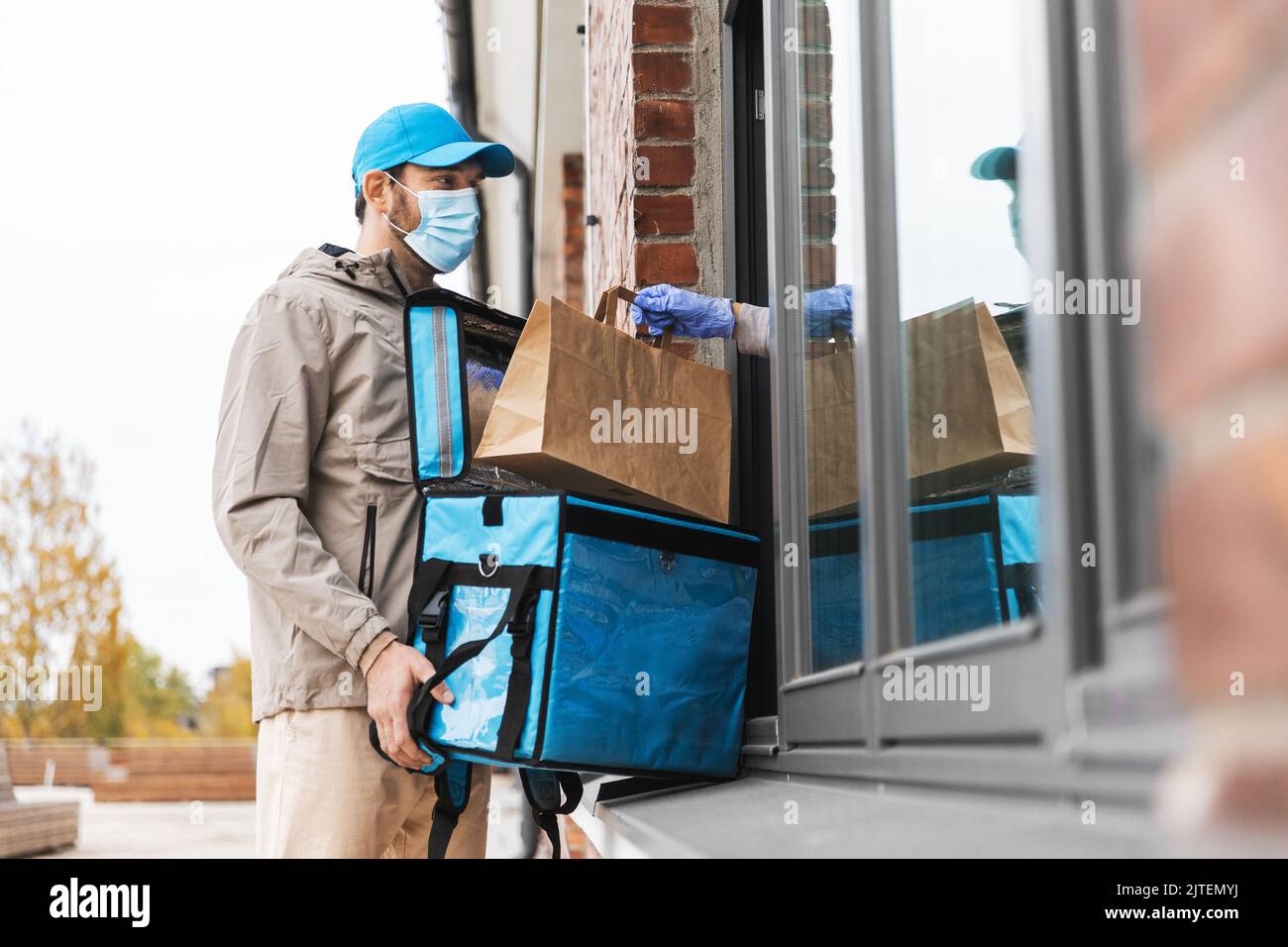 food delivery man in mask giving order to customer Stock Photo - Alamy