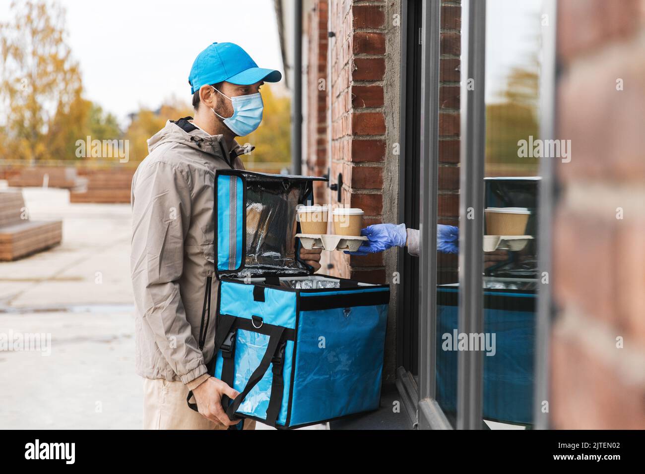food delivery man in mask giving order to customer Stock Photo - Alamy