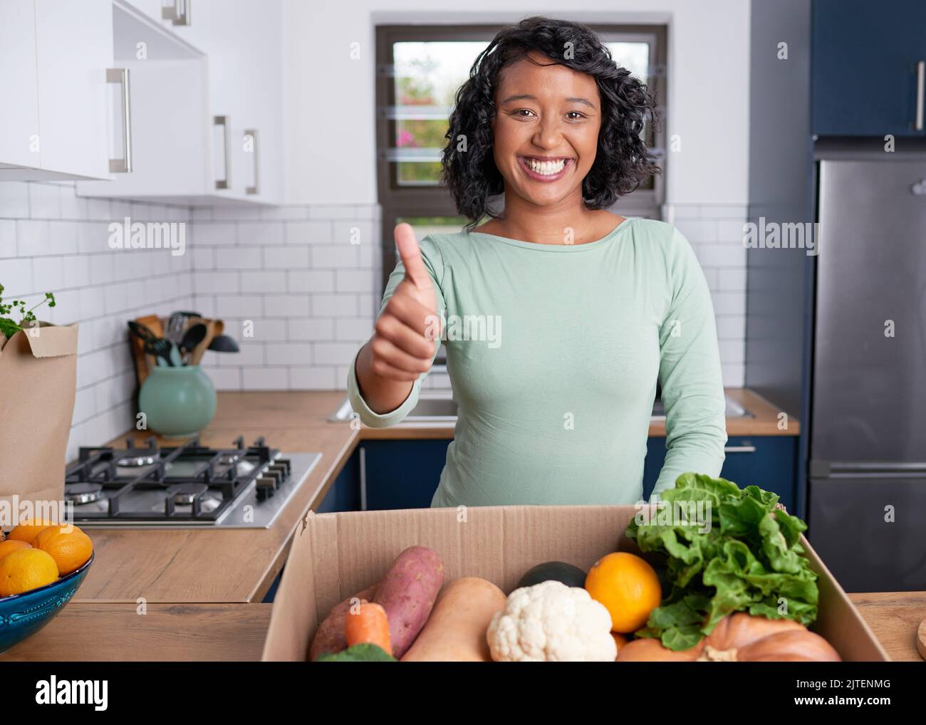 A young multi-ethnic customer gives thumbs up to fruit and veg box delivery Stock Photo