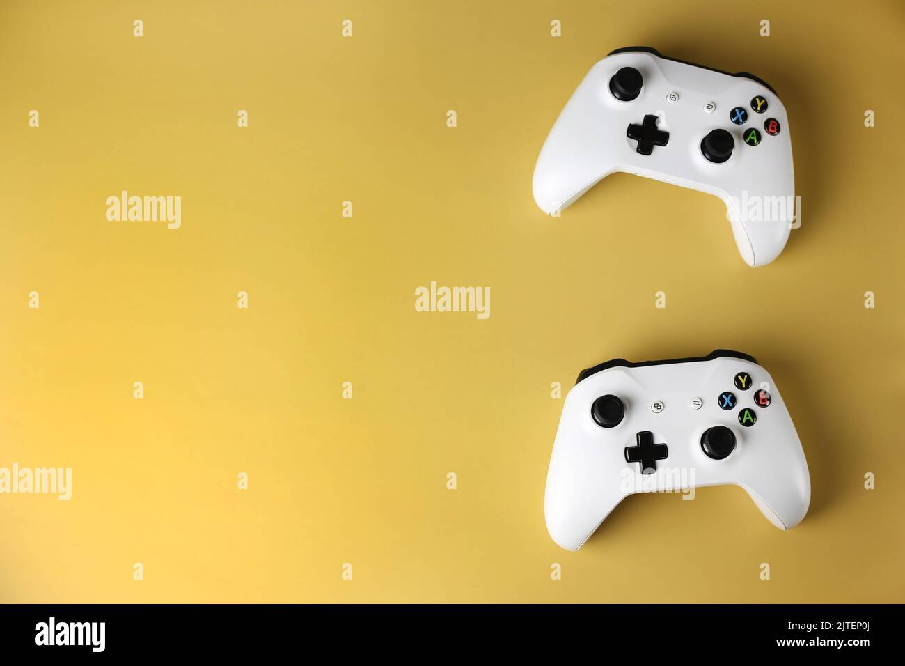 Two gaming gamepads on the side on an isolated yellow background Stock Photo