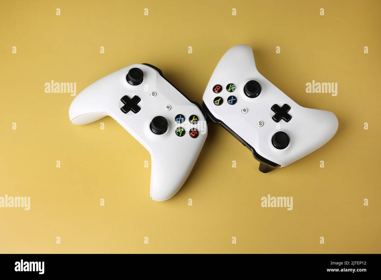 Two gaming gamepads side by side in the center on an isolated yellow