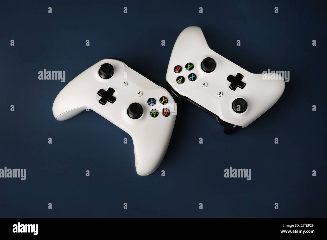 Two gaming gamepads side by side in the center on an isolated dark blue ...
