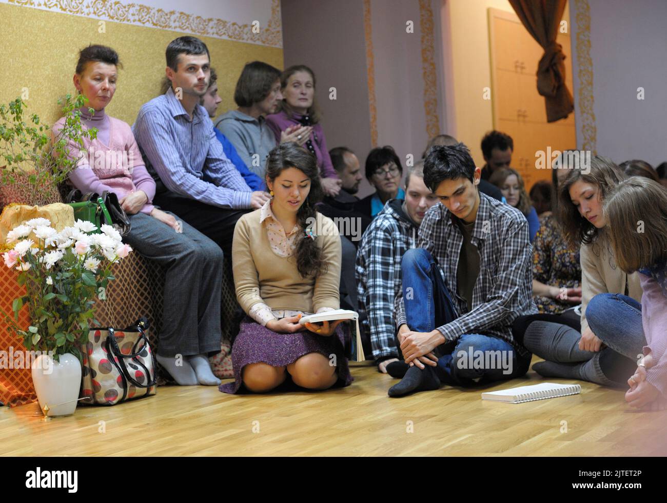 Krishna parishioners sitting on a floor and reading mantra from the book. April 3, 2013. Kyiv, Ukraine Stock Photo