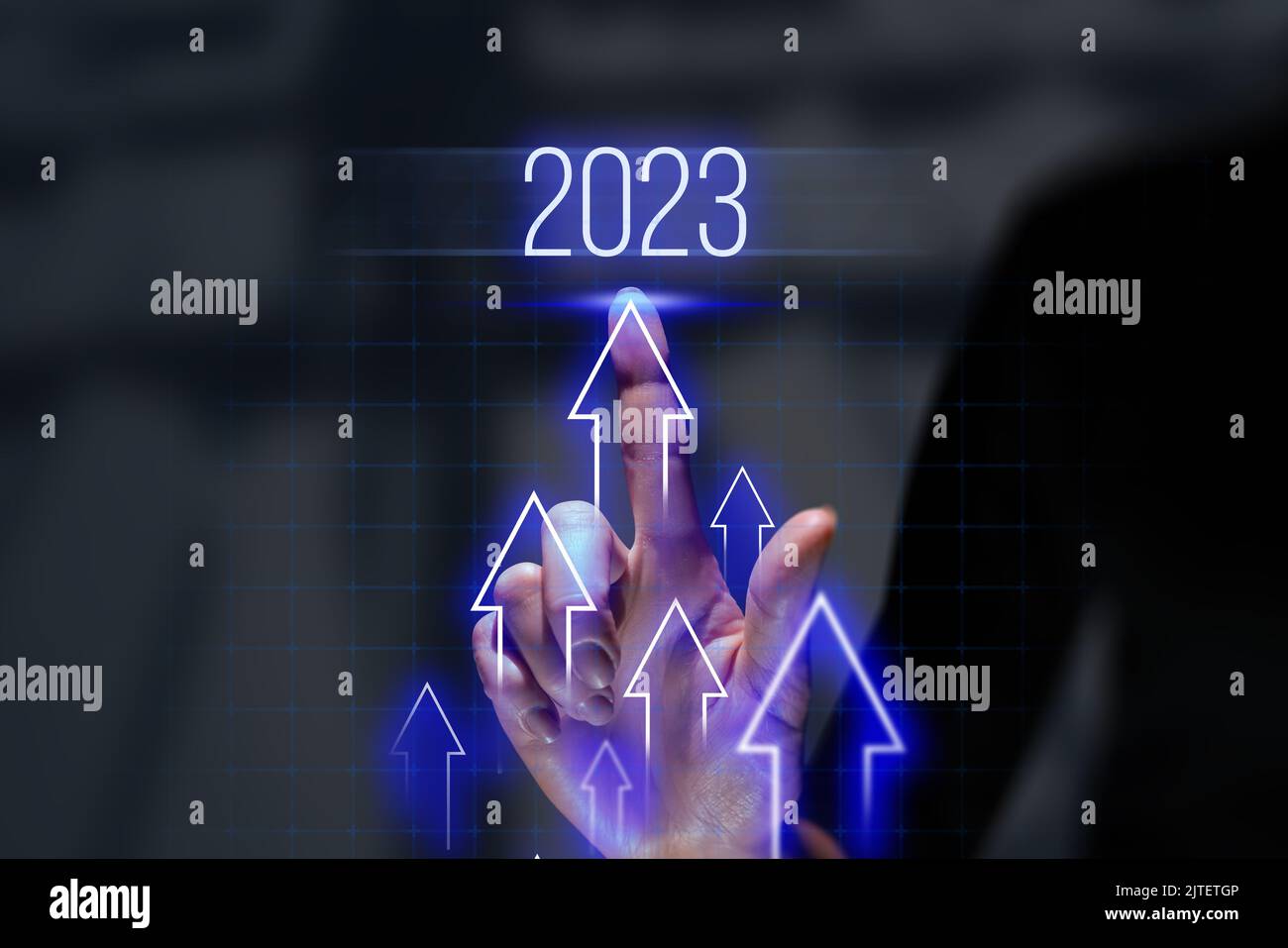 The person touches the hologram with up arrows. Business success and investment growth in 2023. Stock Photo