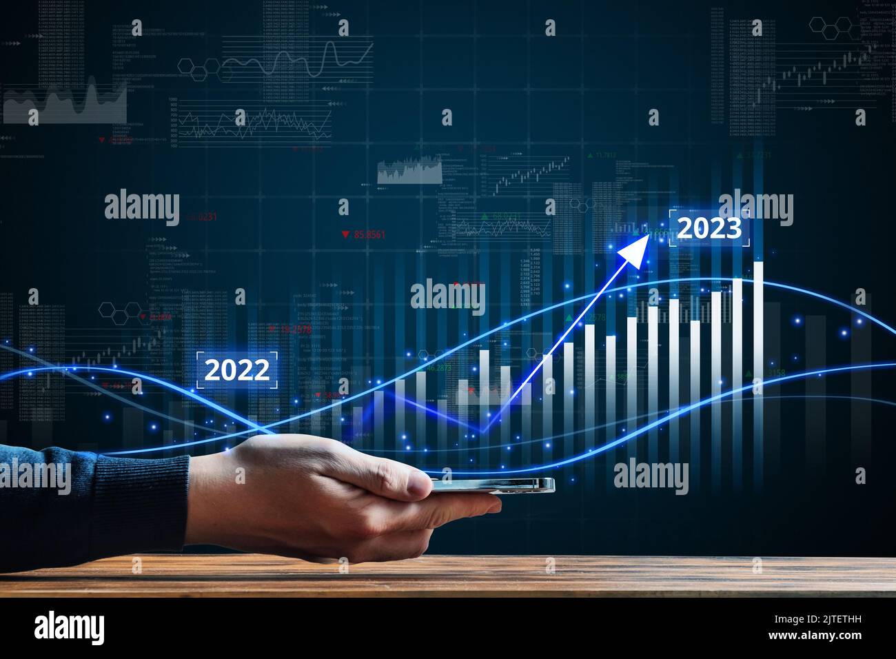 Business growth in 2023. Economic and financial growth. The person is holding smartphone with hologram. Stock Photo