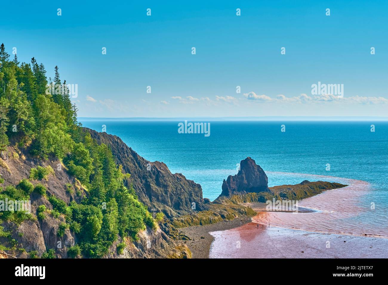 People exploring the ocean floor below 90 meter, 300 foot cliffs as the tide recedes on the Bay of Fundy at Five Islands Nova Scotia. Stock Photo