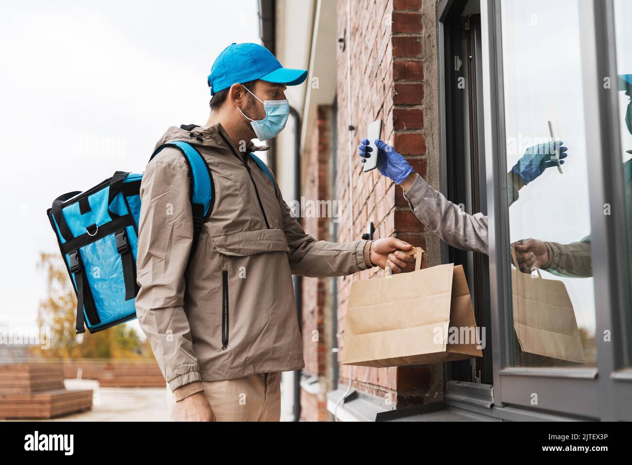 food delivery man in mask giving order to customer Stock Photo - Alamy