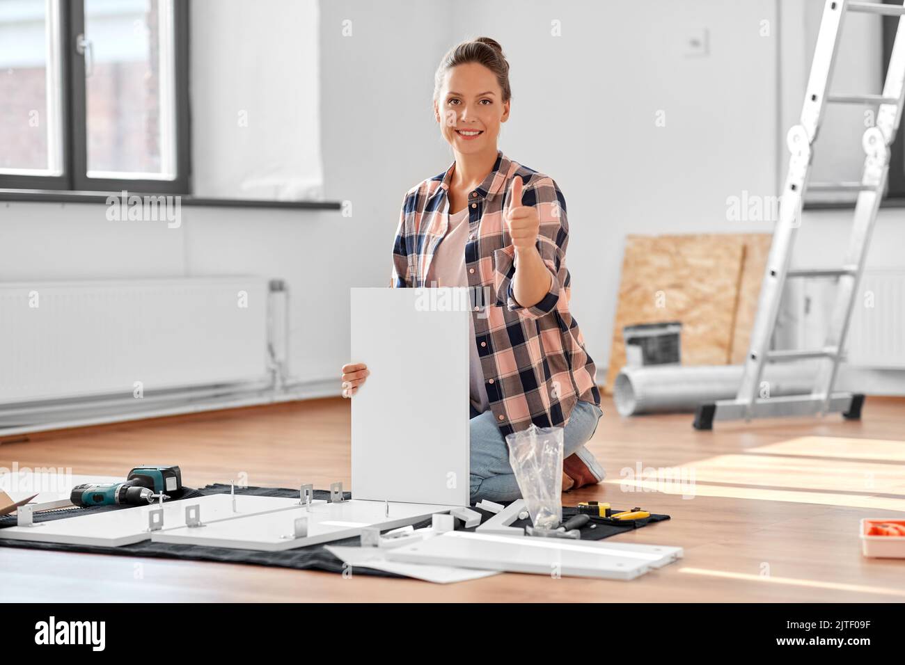 woman assembling furniture and showing thumbs up Stock Photo