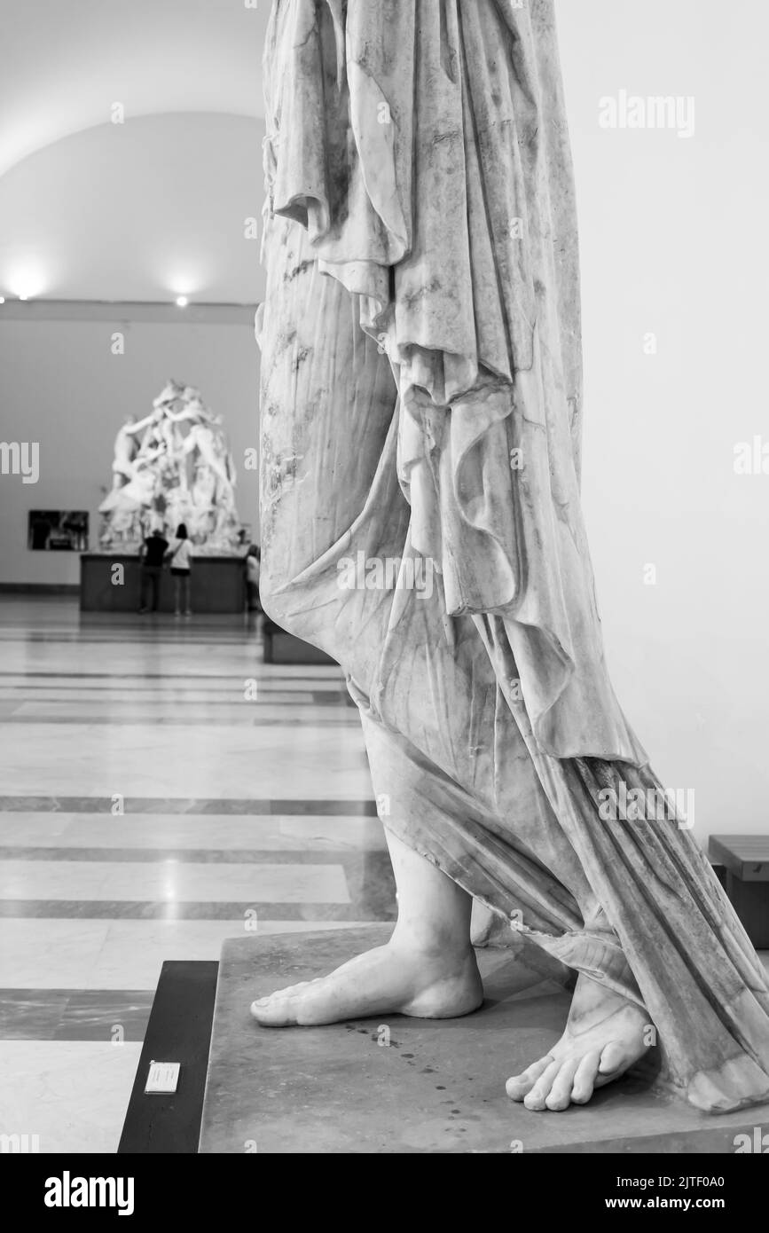 Black and white photo of bottom part of ancient roman statue representing a woman wearing a long draped tunic Stock Photo