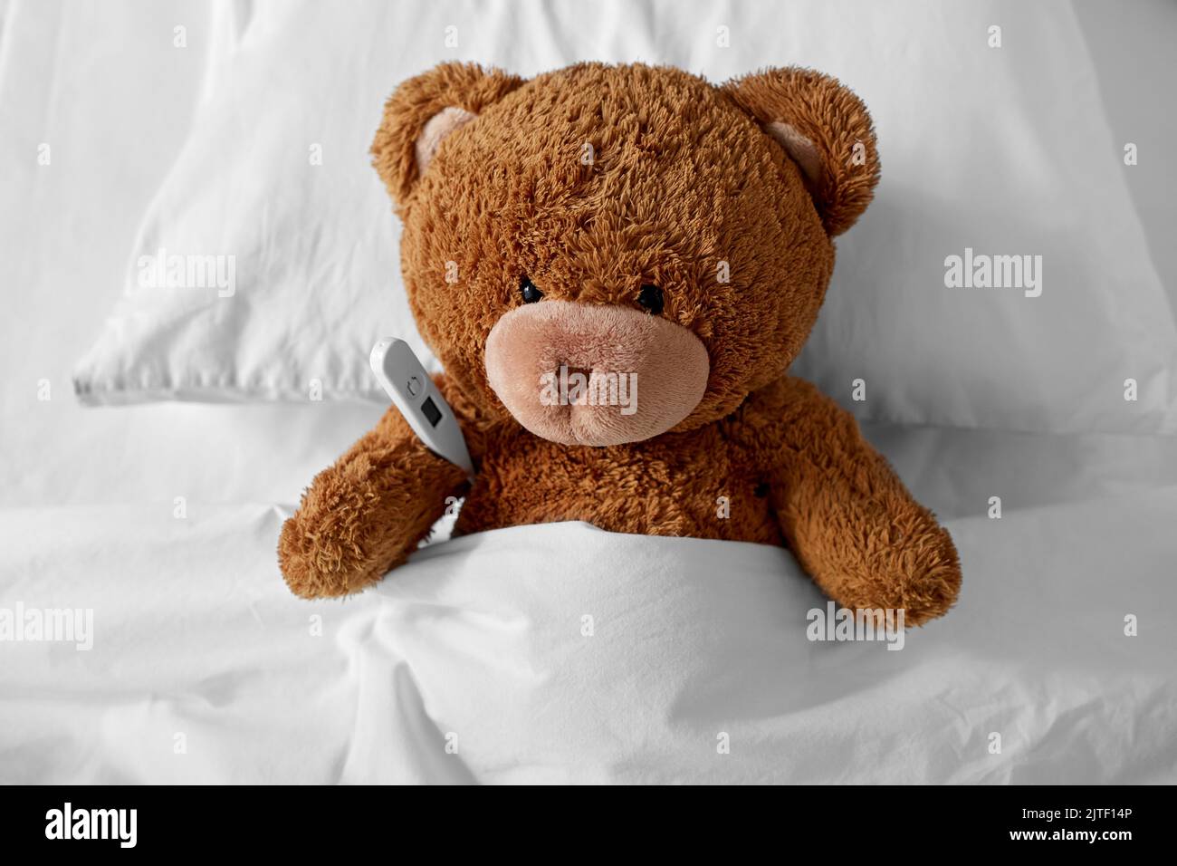ill teddy bear toy head with thermometer in bed Stock Photo - Alamy