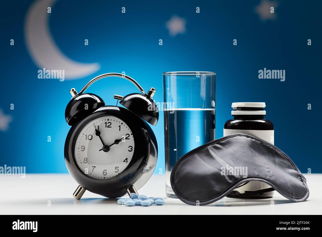 alarm clock, glass of water and sleeping pills Stock Photo