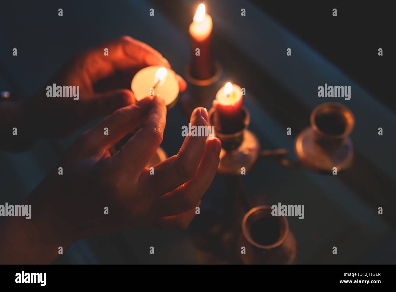 Vintage retro brass candlesticks with red candles burning in a dark