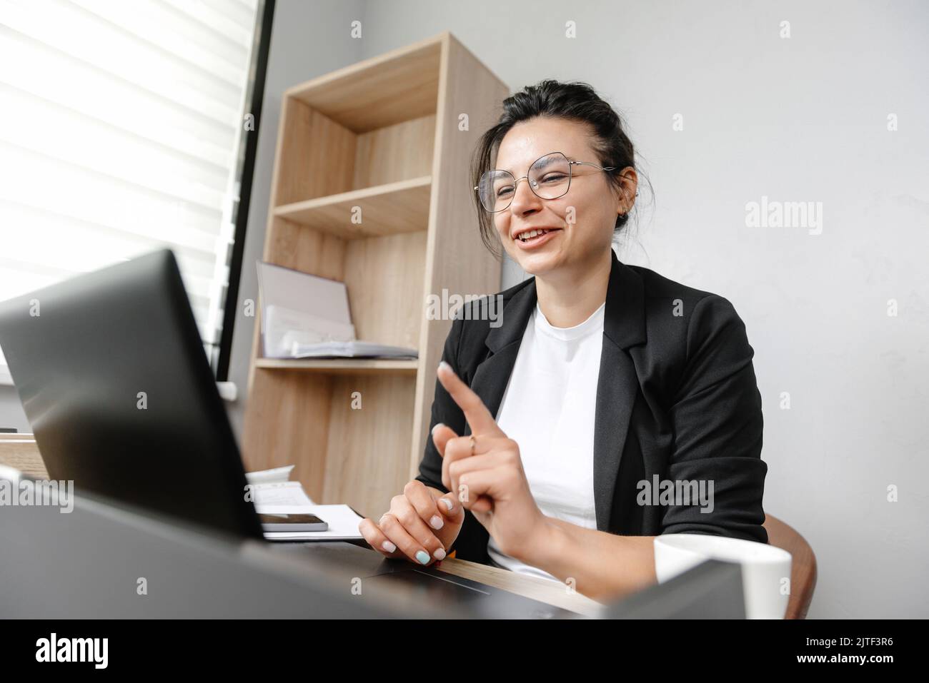 The girl in the office is running an online conference and saying something. Working in an office hybrid work system Stock Photo