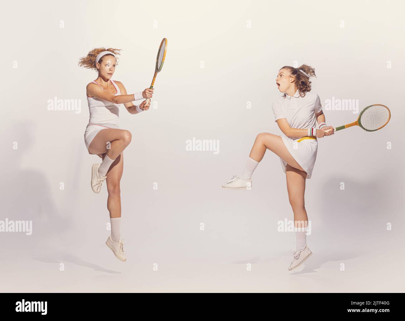 Portrait of young women in retro uniform playing badminton with wooden