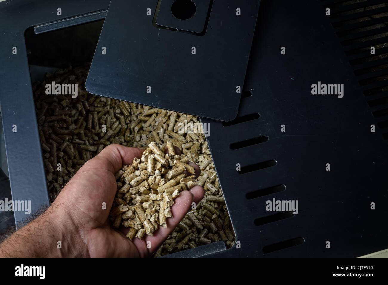 hand holding wood pellets going into the stove compartment, alternative