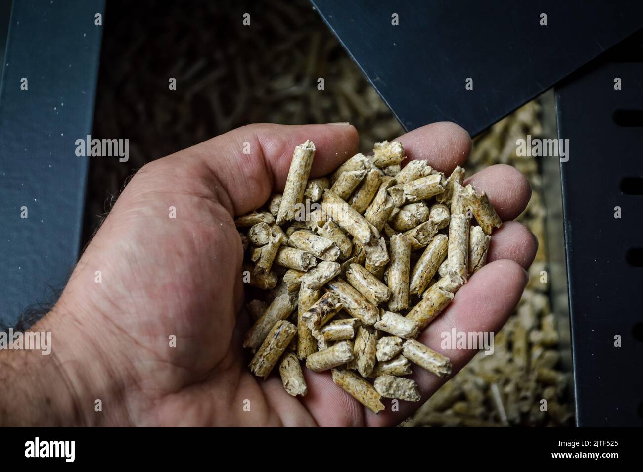 hand holding wood pellets going into the stove compartment, alternative