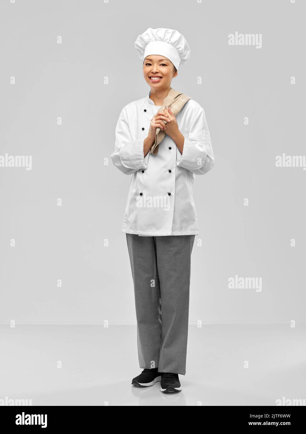 smiling female chef in jacket with kitchen towel Stock Photo