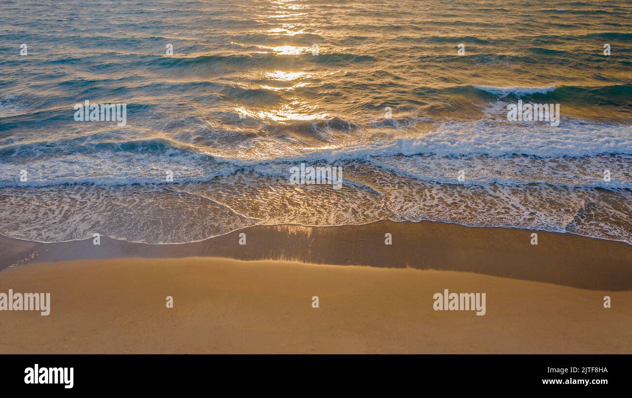 Calm ocean waves rolling onto sandy beach at sunrise Stock Photo - Alamy