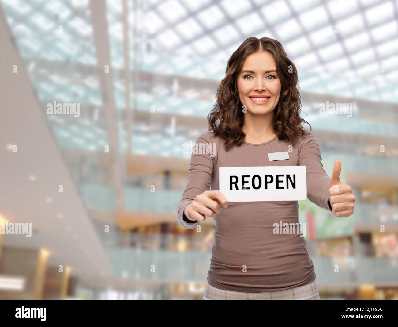 shop assistant with reopen sign showing thumbs up Stock Photo - Alamy
