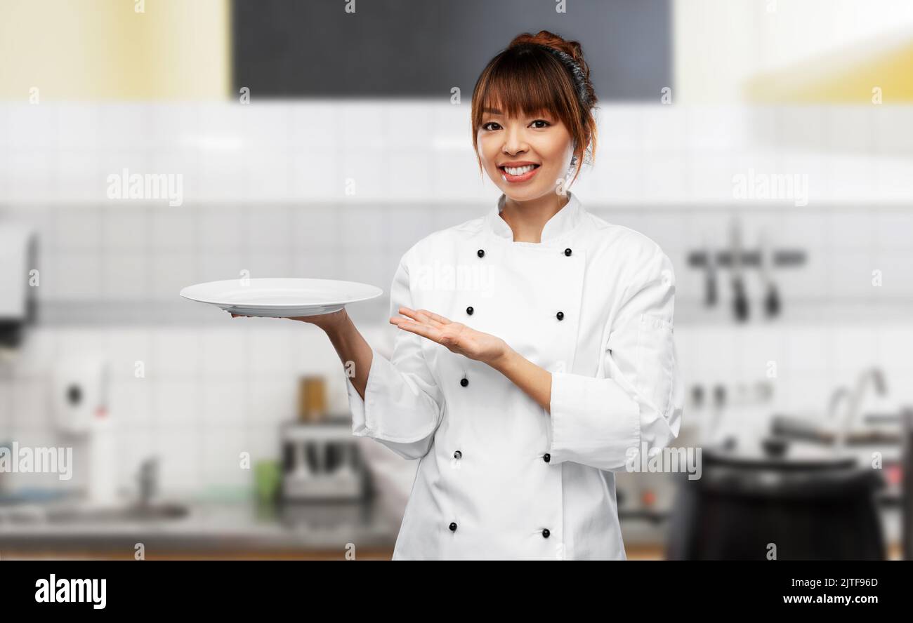 happy smiling female chef holding empty plate Stock Photo