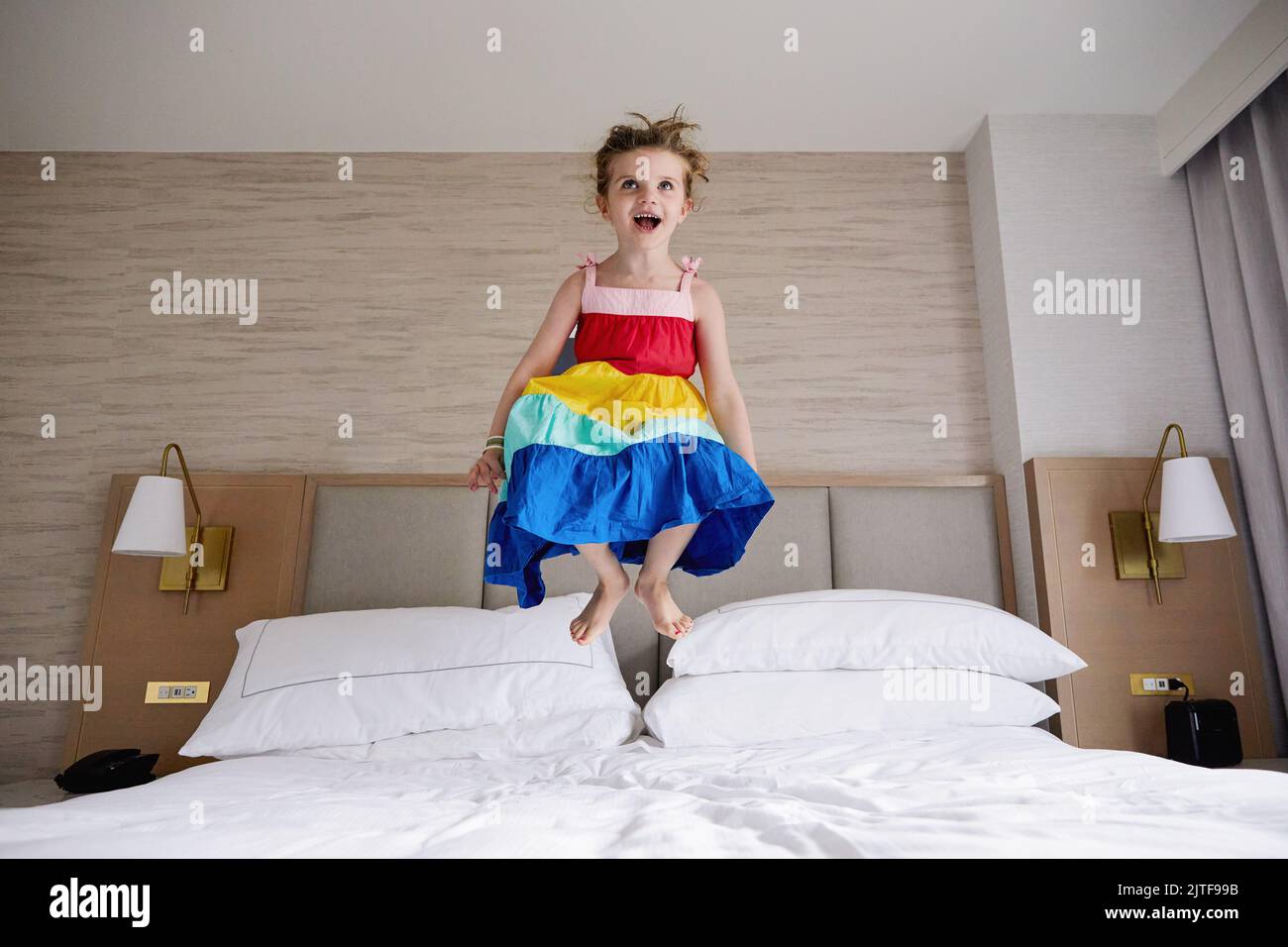 Smiling girl (4-5) jumping on bed Stock Photo