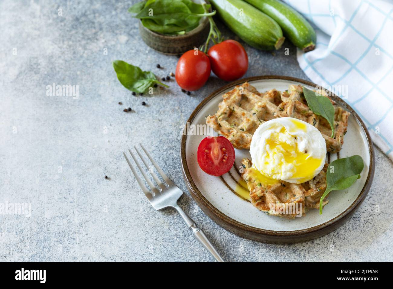 Spinach and zucchini vegan waffles with a poached egg on a stone