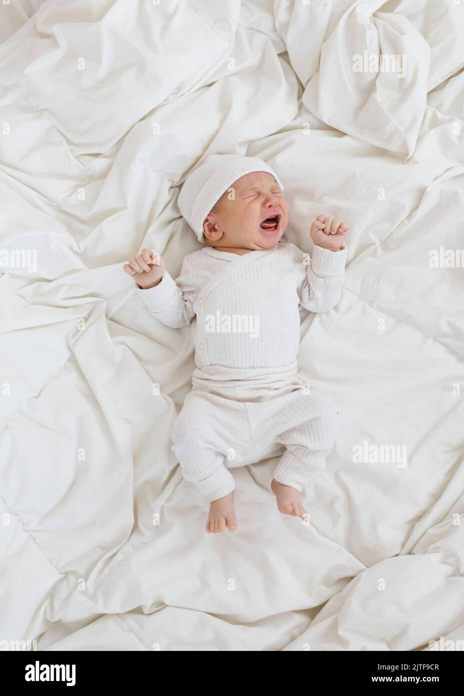 Overhead view of newborn boy (0-1 months) crying on bed Stock Photo