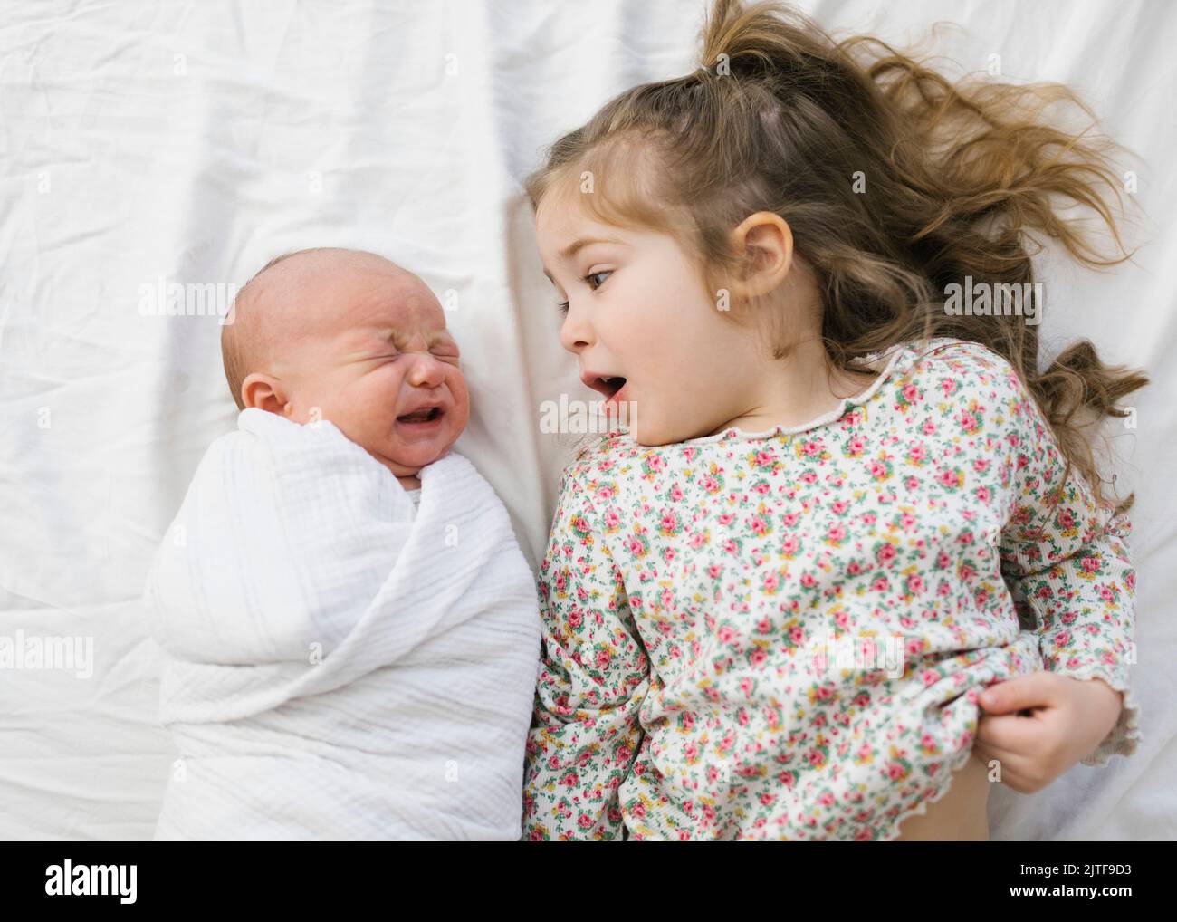 Overhead view of girl (2-3) with newborn (0-1 months) brother on bed Stock Photo