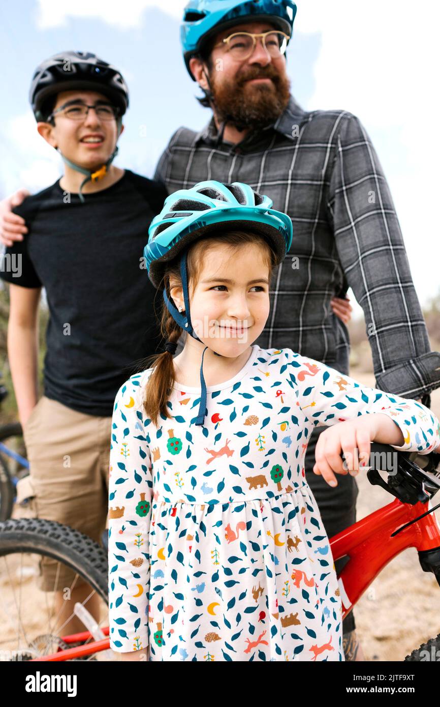Father with children (8-9, 14-15) wearing bike helmets Stock Photo