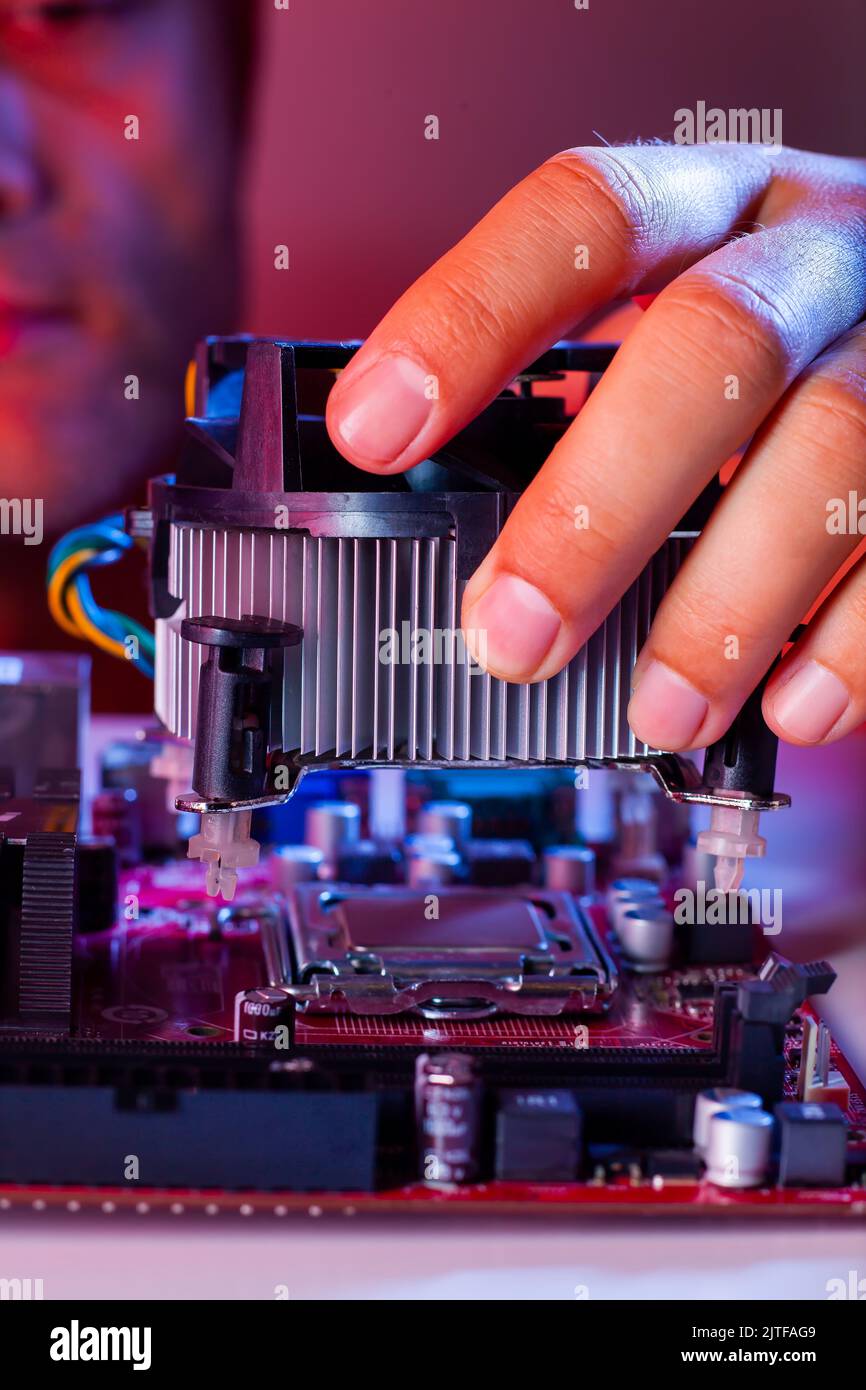 A man's hand inserts a cooler into the motherboard socket. Stock Photo