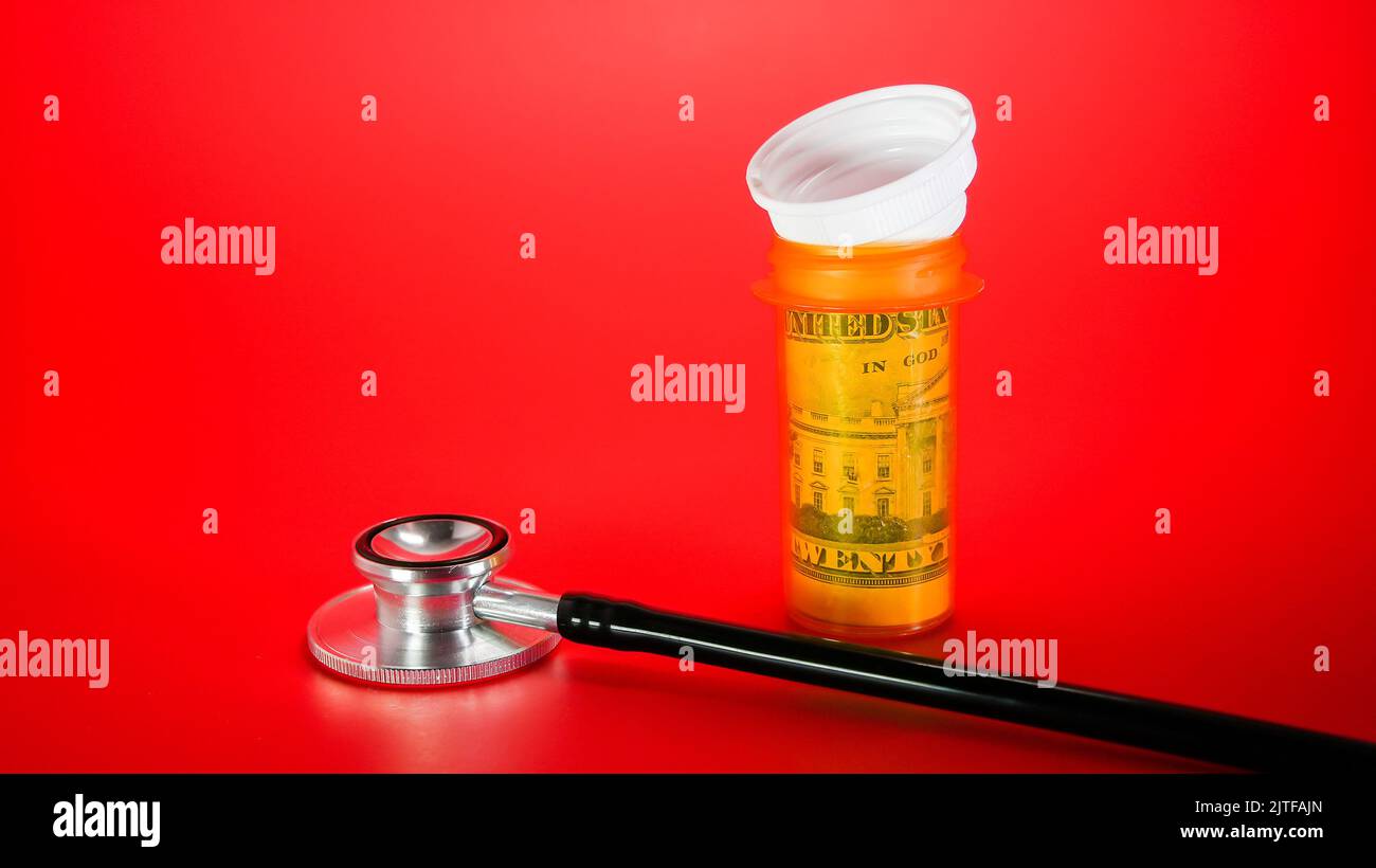 Stethoscope with plastic container for pills with dollar cash inside on red background with copy space Stock Photo