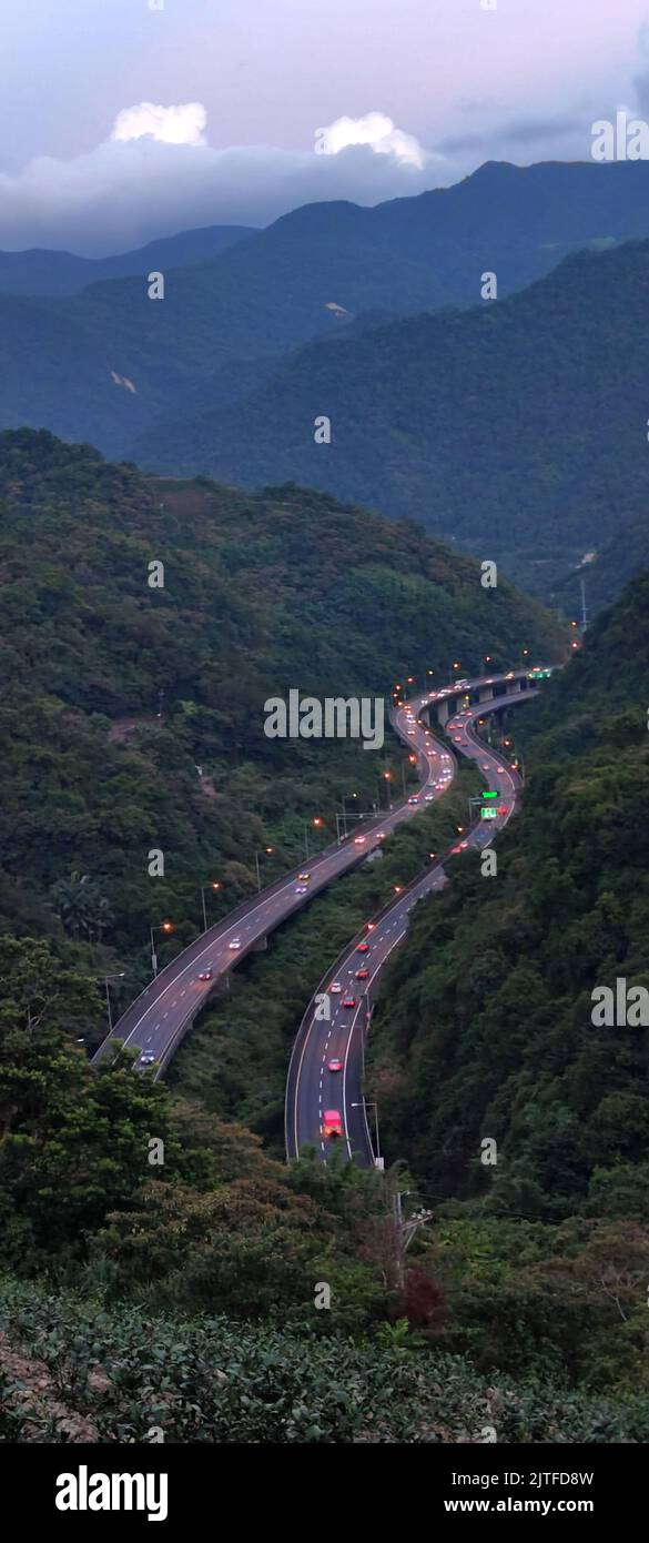 The curved highway through the green rice fields with houses scattered throughout the plain in Yilan, Taiwan  Aerial view of National Freeway No.5, T Stock Photo