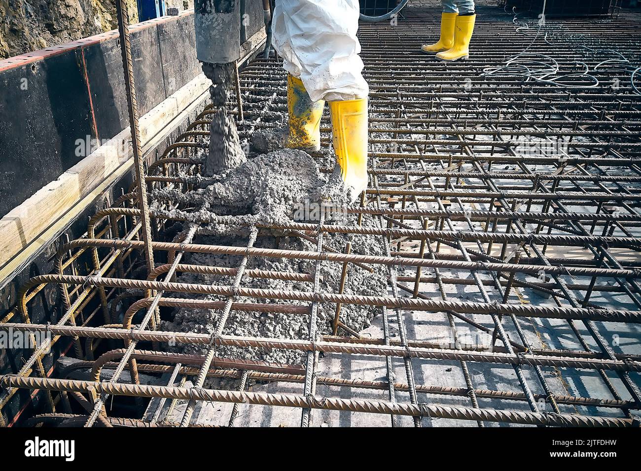 Construction workers are pouring concrete to formwork Stock Photo