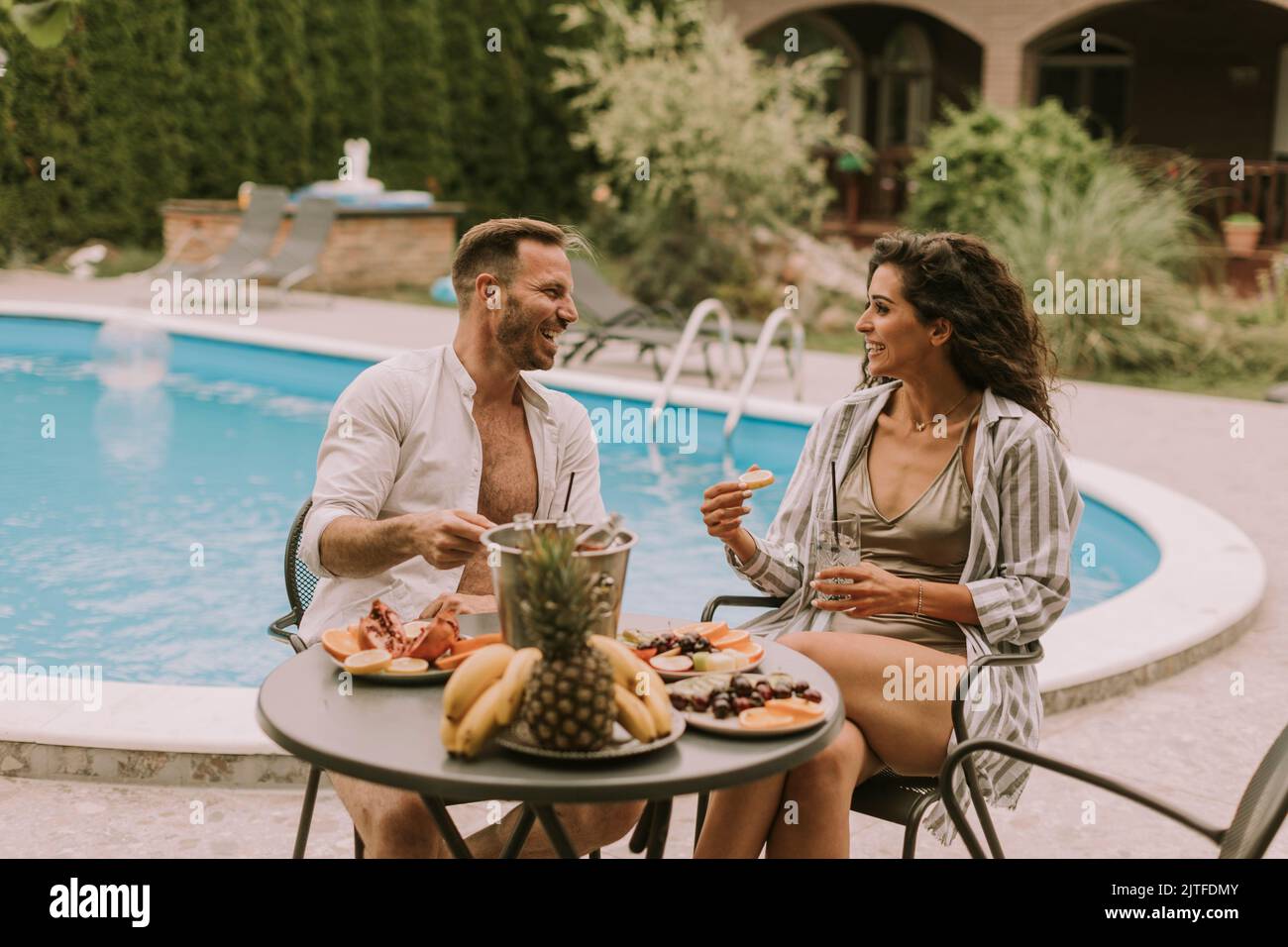 Handsome young couple sitting in the backyard, drinking lemande and