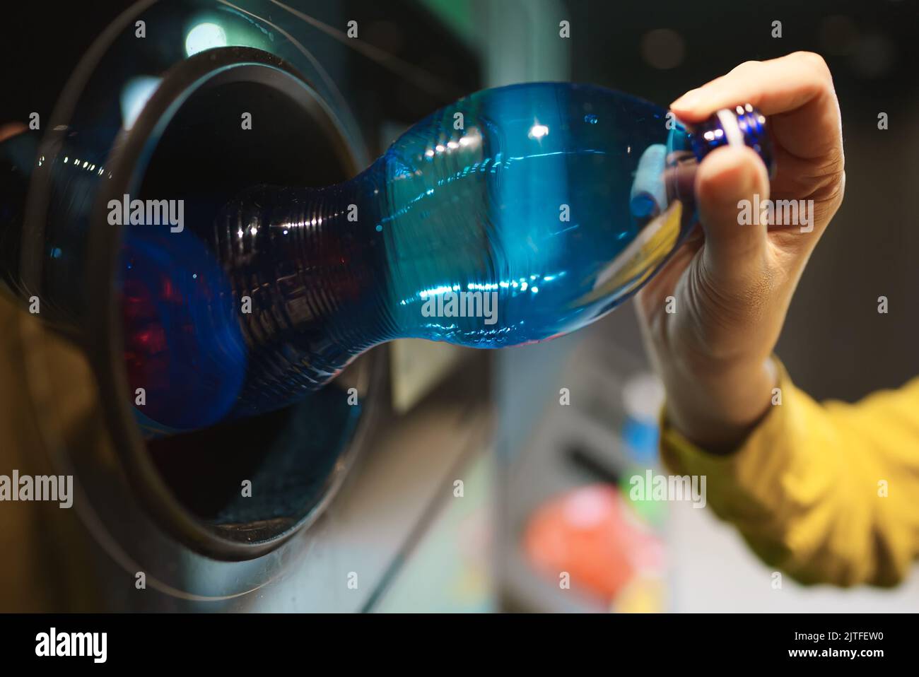 Woman puts bottle in automatic bottle recycling machine. Reverse