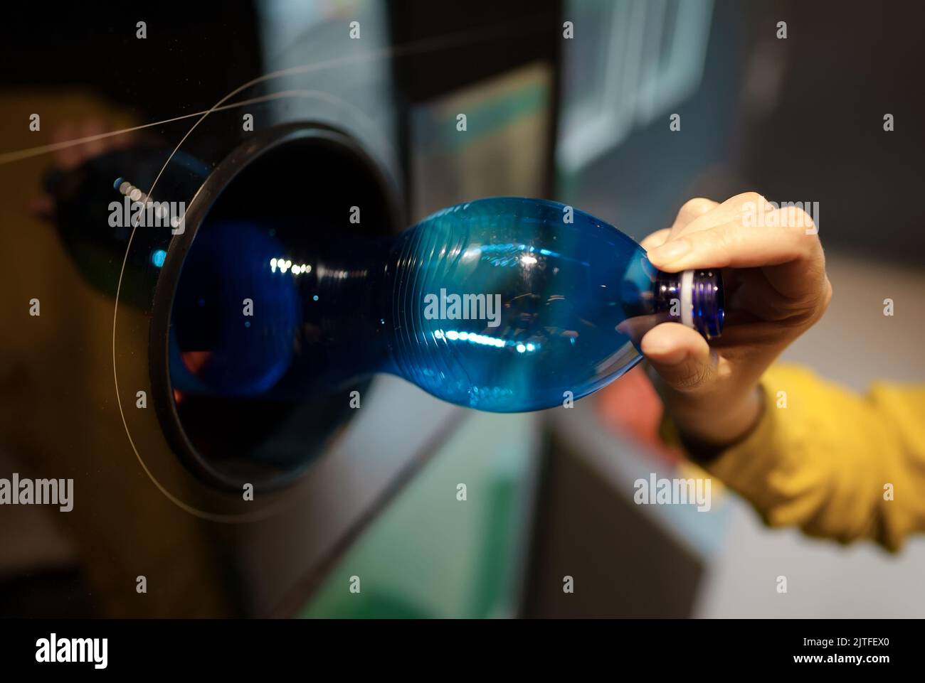 Woman puts bottle in automatic bottle recycling machine. Reverse