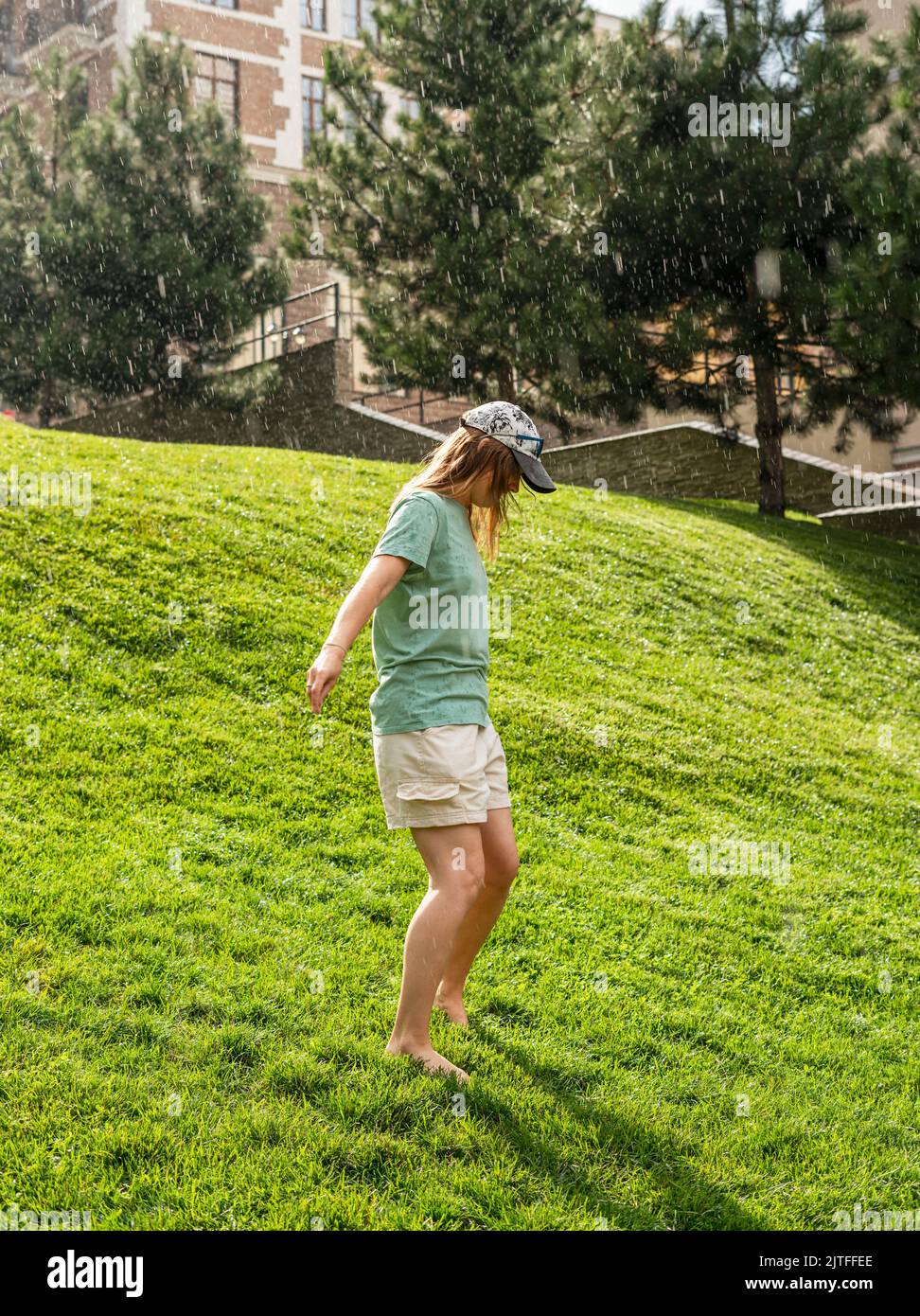 happy young woman barefoot walking on green grass lawn enjoying the ...