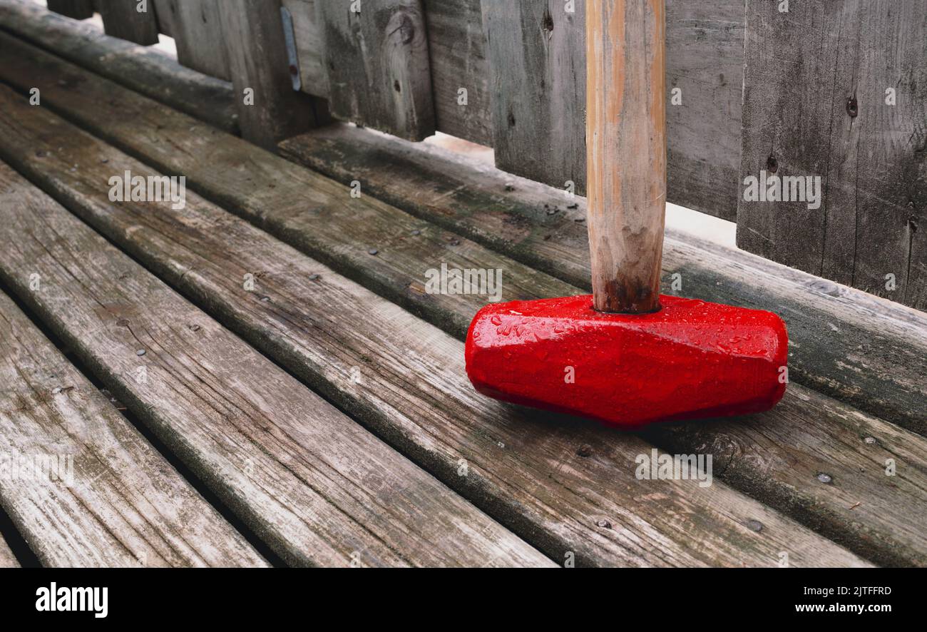 Sledge hammer on weathered wooden deck boards Stock Photo