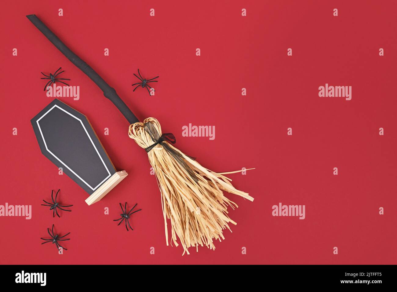 Halloween witch broom, coffin shaped chalkboard and spiders on dark red background with copy space Stock Photo