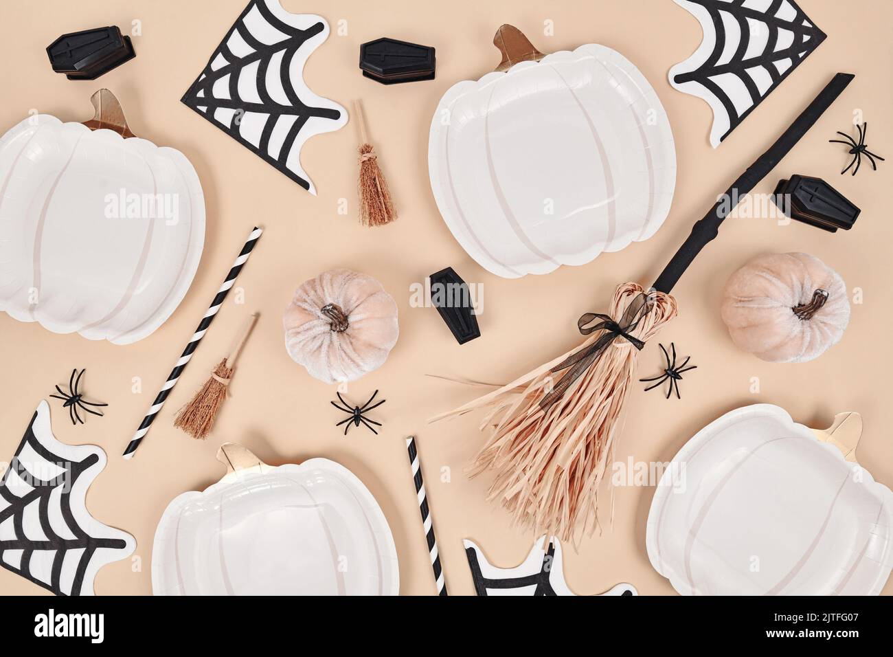 Beige Halloween party flat lay with pumpkin shaped plates, witch broom, spiders and coffins Stock Photo